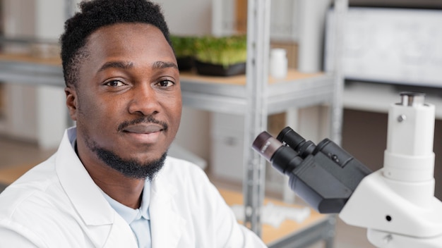 Investigador masculino sonriente en el laboratorio con microscopio