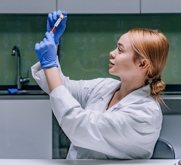 Investigador médico o científico femenino mirando un tubo de ensayo en un laboratorio.