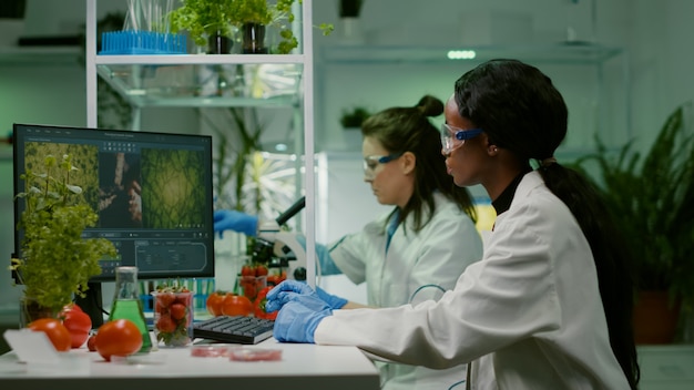 Investigador químico inyectando fresa con líquido de ADN orgánico mientras trabajaba en un laboratorio de cultivo farmacéutico