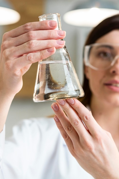 Foto gratuita investigadora con gafas de seguridad con tubo de ensayo en el laboratorio