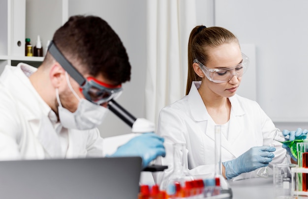 Investigadora con guantes y tubos de ensayo en el laboratorio.