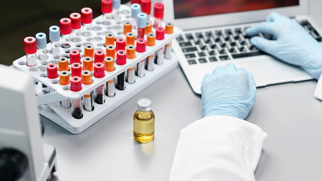 Investigadora en el laboratorio con frasco de vacuna y tubos de ensayo