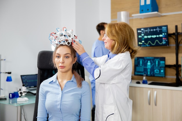 Foto gratuita investigadora que coloca un dispositivo de escaneo de ondas cerebrales en una paciente. estudio clínico de la actividad cerebral