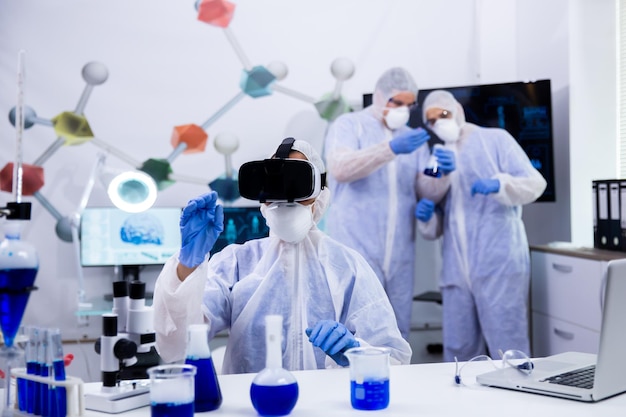 Investigadora utilizando simulación de gafas de realidad virtual para experimentos químicos en el laboratorio de investigación moderno.