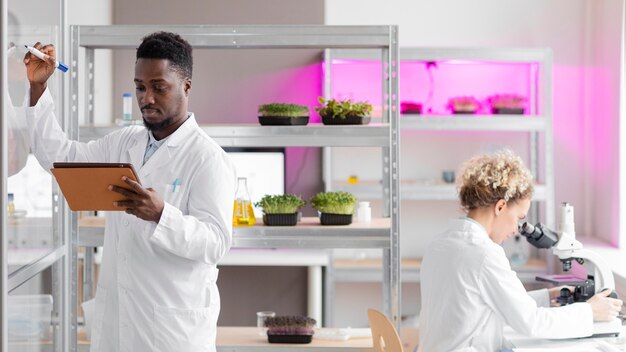 Investigadores en el laboratorio de biotecnología con tableta y microscopio