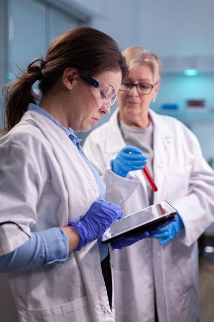 Investigadores químicos médicos en bata blanca analizando el tubo de ensayo de sangre en el laboratorio equipado