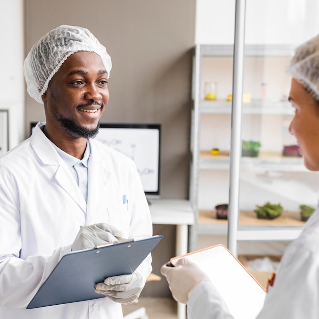 Investigadores de Smiley en el laboratorio de biotecnología con portapapeles y tableta