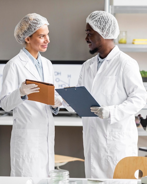 Foto gratuita investigadores de smiley en el laboratorio de biotecnología con tableta y portapapeles