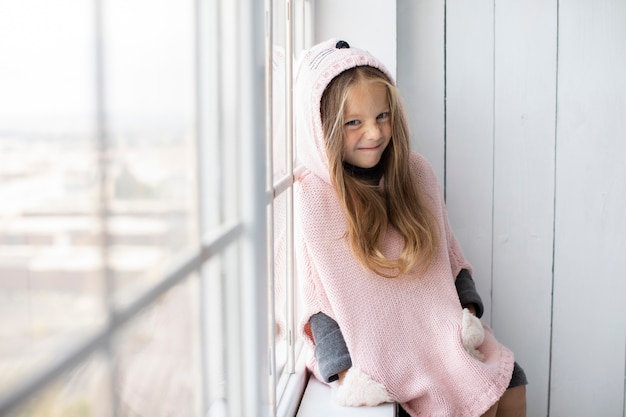 Invierno vestida niña junto a una ventana