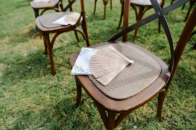 Foto gratuita invitación de invitado, abanico de mano en la silla con clase antigua marrón al aire libre