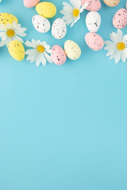 Invitación de Pascua con huevos y margaritas sobre un fondo azul con espacio de copia