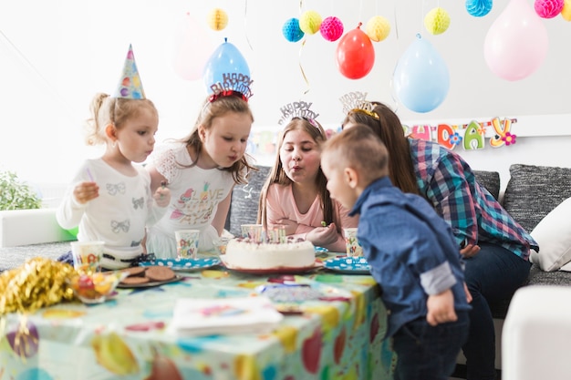 Invitados soplando velas en el pastel