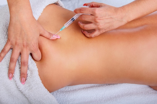 Inyección de jeringa en la espalda de la mujer. Mujer disfrutando de un relajante masaje de espalda en el centro de spa de cosmetología.