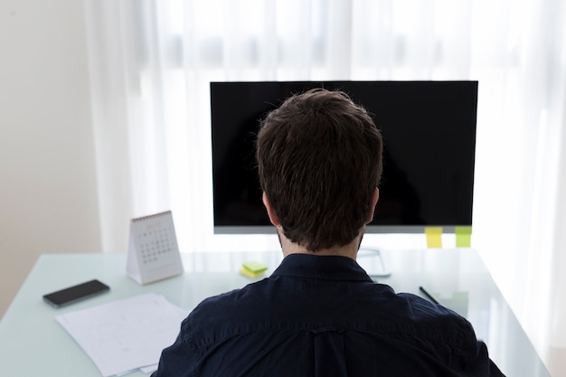 Irreconocible hombre navegando por la computadora en la oficina