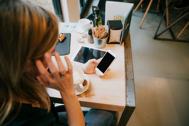 Irreconocible mujer navegación smartphone en café