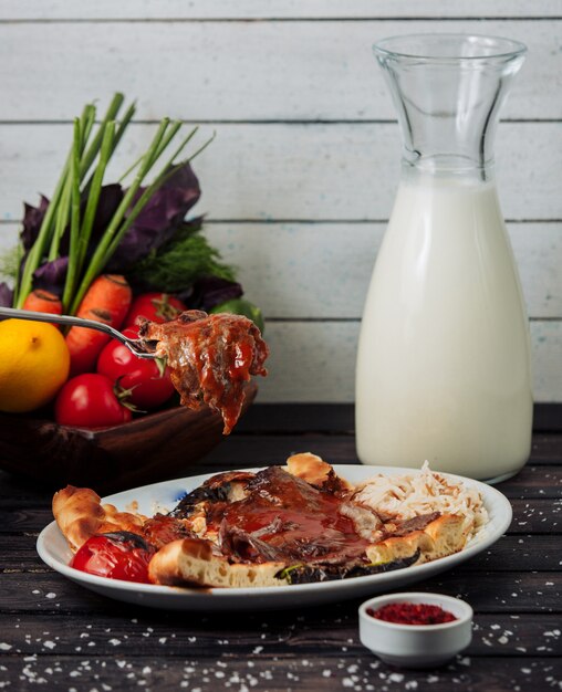 Iskender doner con una botella de ayran sobre la mesa