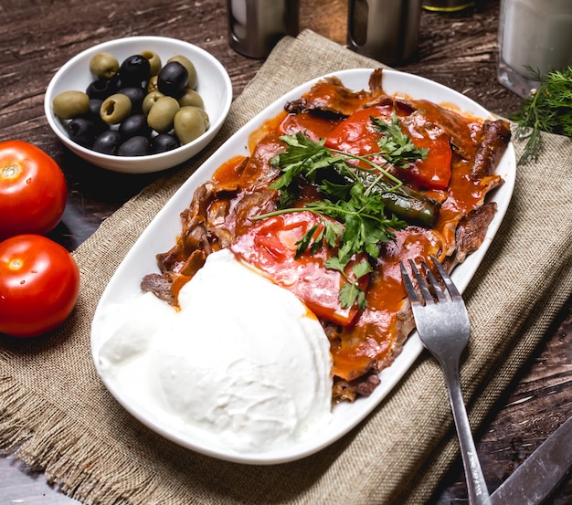 Iskender kebab adornado con tomate y perejil servido con yogurt