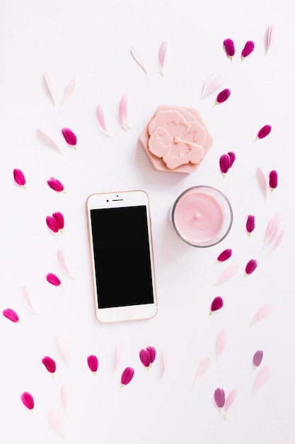 Foto gratuita jabón floral; vela y smartphone decorados con pétalos de flores sobre fondo blanco.