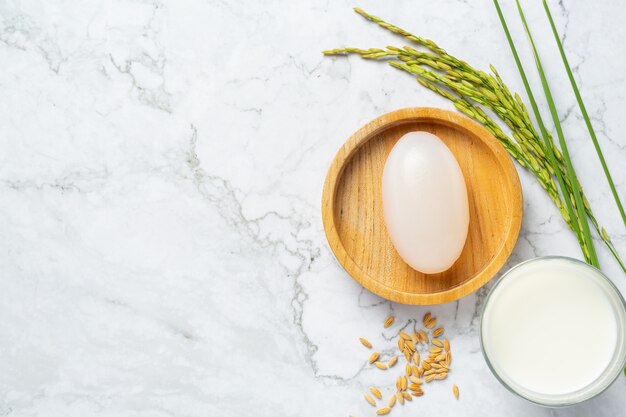 Jabón de leche de arroz, glss de leche, plantas de arroz y semillas de arroz colocadas en un piso de mármol blanco