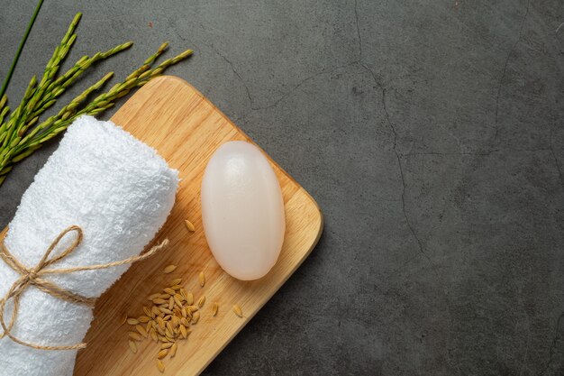 Jabón de leche de arroz, toalla enrollada, plantas de arroz y semillas de arroz en prueba de madera