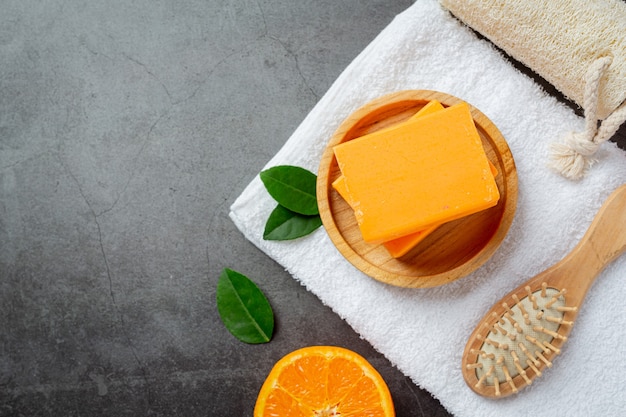 Jabón de naranja con naranja fresca sobre fondo oscuro