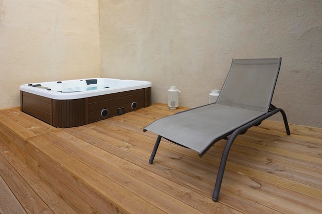 Jacuzzi y tumbona en suelo de madera.