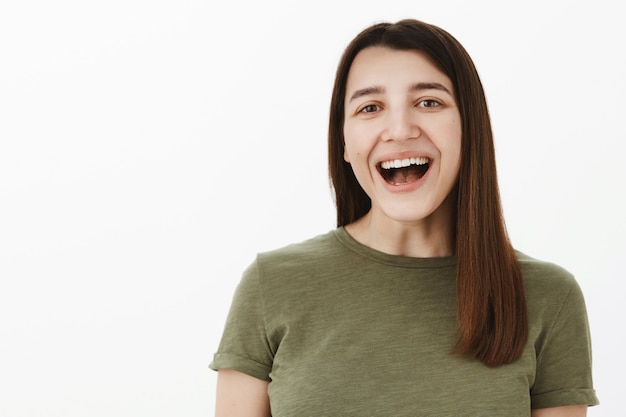 Jaja muy gracioso. Retrato de niña divertida y despreocupada que se divierte riendo a carcajadas con la boca abierta mirando encantada y entretenida viendo un programa de televisión hilarante, bromeando sobre una pared gris