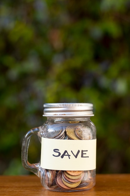 Jar con monedas y guardar la etiqueta con fondo borroso