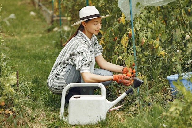 Jardinería en verano. Mujer regando las flores con una regadera. Chica con sombrero.