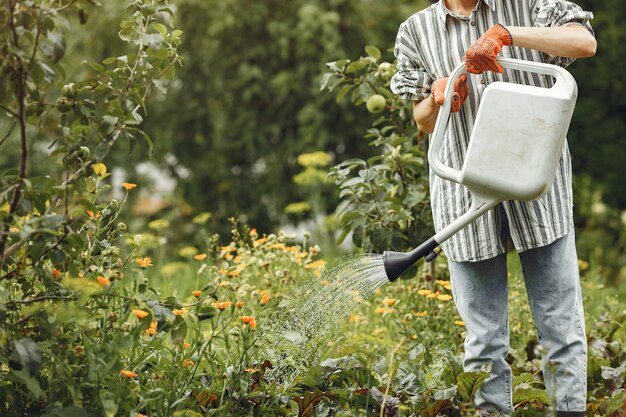 Jardinería en verano. Mujer regando las flores con una regadera. Chica con sombrero.