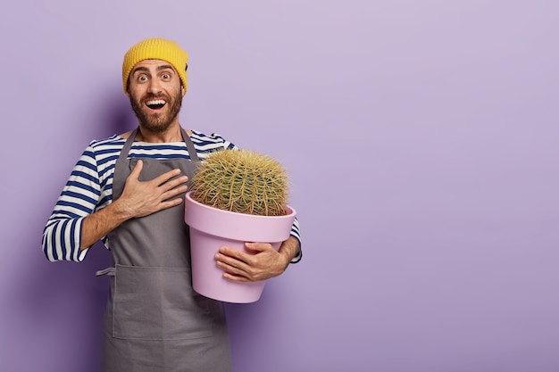 Jardinero feliz se siente agradecido con su amigo por obtener una nueva raza de cactus en su colección de jardín, mantiene la mano en el pecho