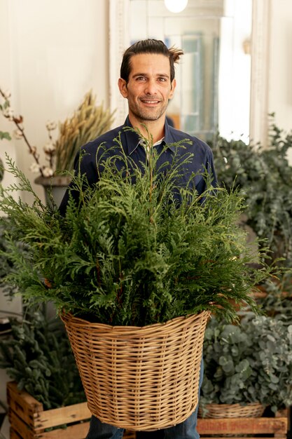 Jardinero hombre con cabello largo sosteniendo una canasta con hojas