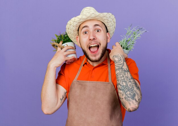 Jardinero macho sorprendido con sombrero de jardinería tiene macetas sobre los hombros