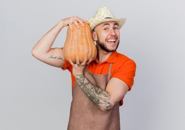 Jardinero masculino alegre vistiendo sombrero de jardinería tiene calabaza