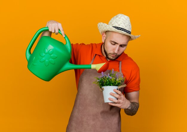 Jardinero masculino confiado con sombrero de jardinería tiene regadera para regar las flores