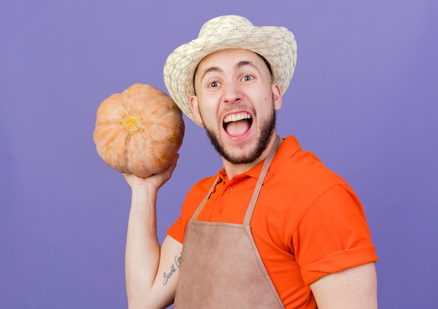 Jardinero masculino emocionado vistiendo sombrero de jardinería tiene calabaza