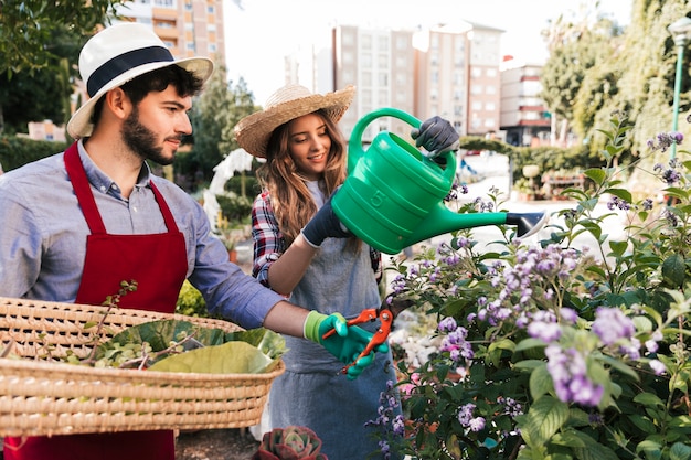 Foto gratuita jardinero masculino y femenino regando y recortando la flor con tijeras de podar