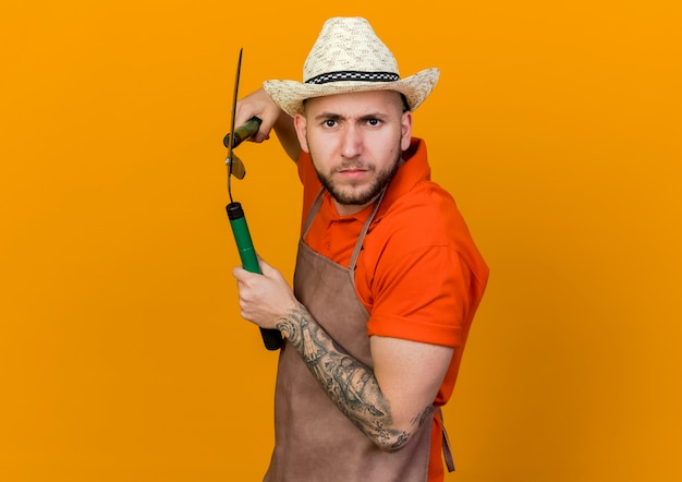 Jardinero masculino serio con sombrero de jardinería sosteniendo tijeras