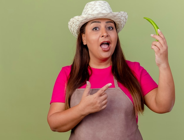 Jardinero de mediana edad mujer en delantal y sombrero con ají verde