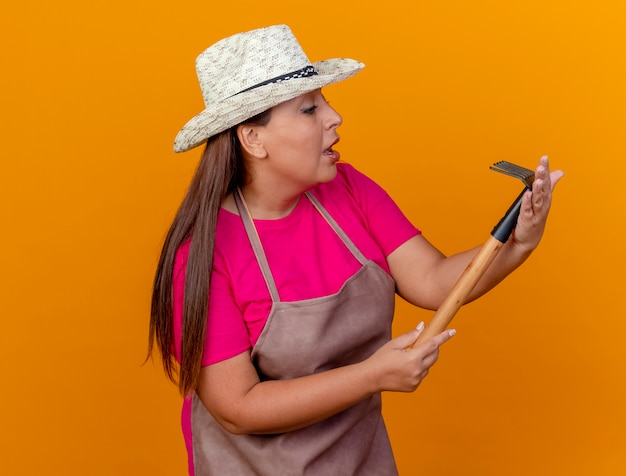 Foto gratuita jardinero de mediana edad mujer en delantal y sombrero con mini rastrillo