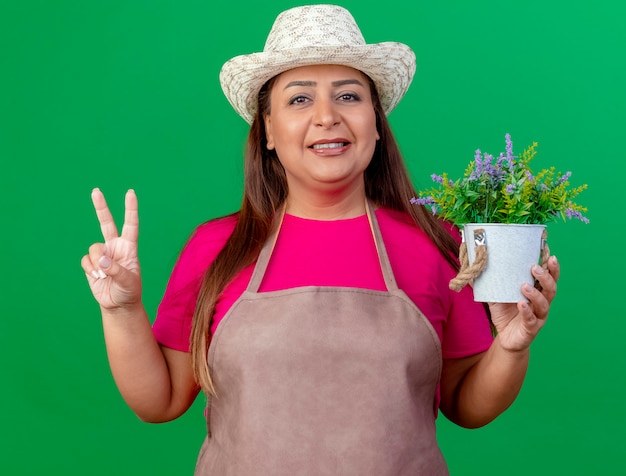 Jardinero de mediana edad mujer en delantal y sombrero sosteniendo macetas