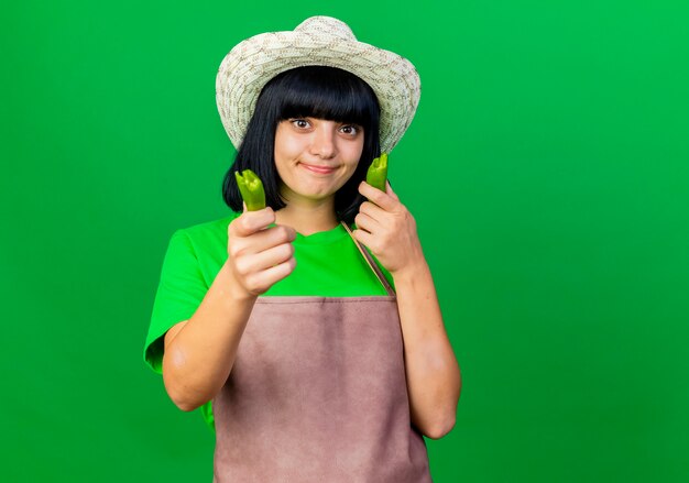 Jardinero mujer joven molesto en uniforme vistiendo sombrero de jardinería tiene pimienta rota