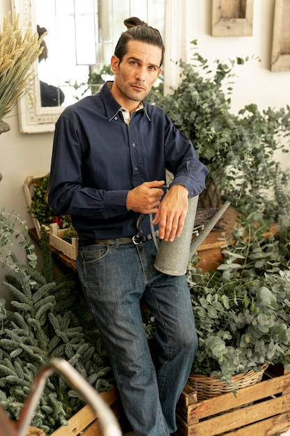Foto gratuita jardinero rodeado de plantas con una regadera