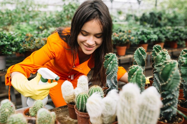 Jardinero de sexo femenino feliz que rocía el agua en las plantas suculentas