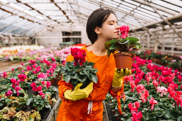 Foto gratuita jardinero de sexo femenino hermoso que huele las flores rosadas