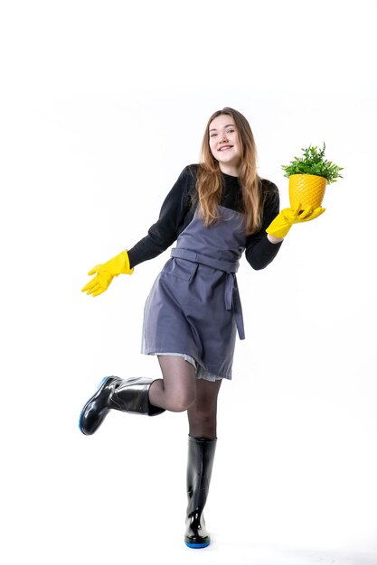 Jardinero de sexo femenino de la vista frontal en guantes amarillos que sostienen la pequeña planta en blanco