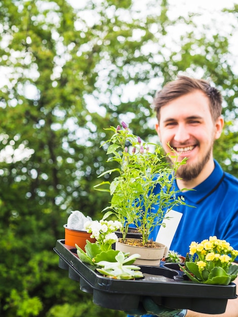 Jardinero de sexo masculino sonriente que sostiene la planta en conserva plástica