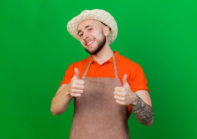 Jardinero sonriente hombre vestido con sombrero de jardinería pulgar hacia arriba con las dos manos