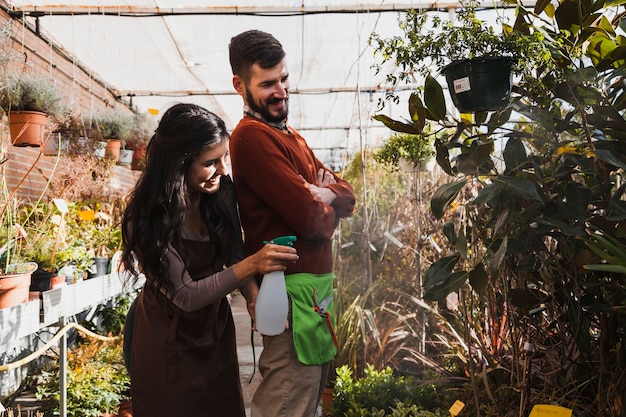 Jardineros sonrientes rociando plantas