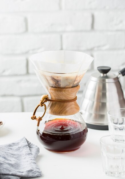 Jarra de café de vidrio cerca de una tetera gris sobre una mesa